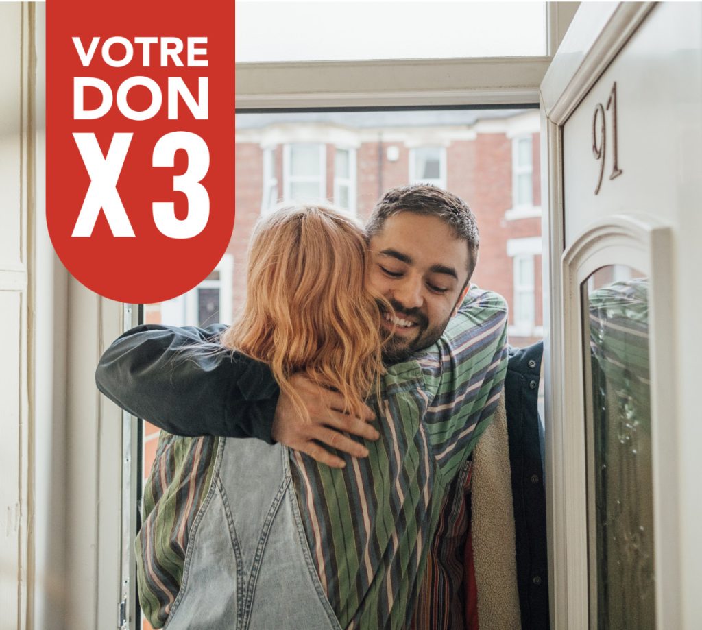 Two people hugging at a front door of a home.