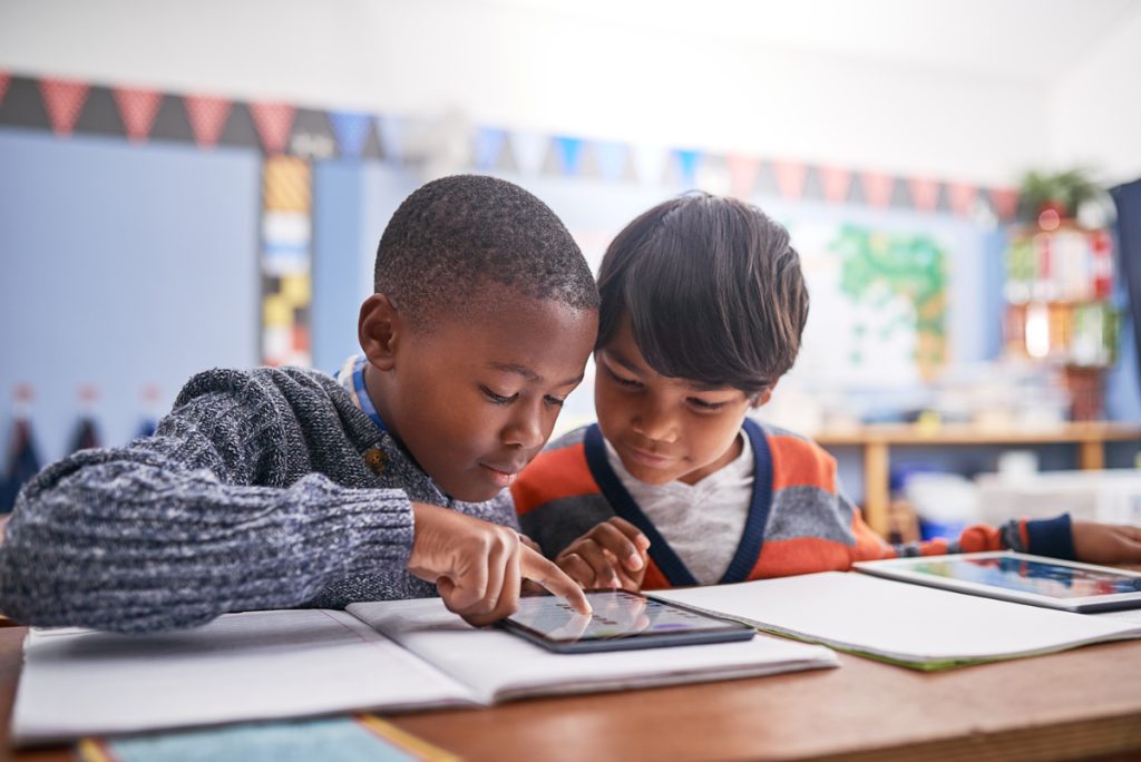 Two kids working on a project together in a school classroom.